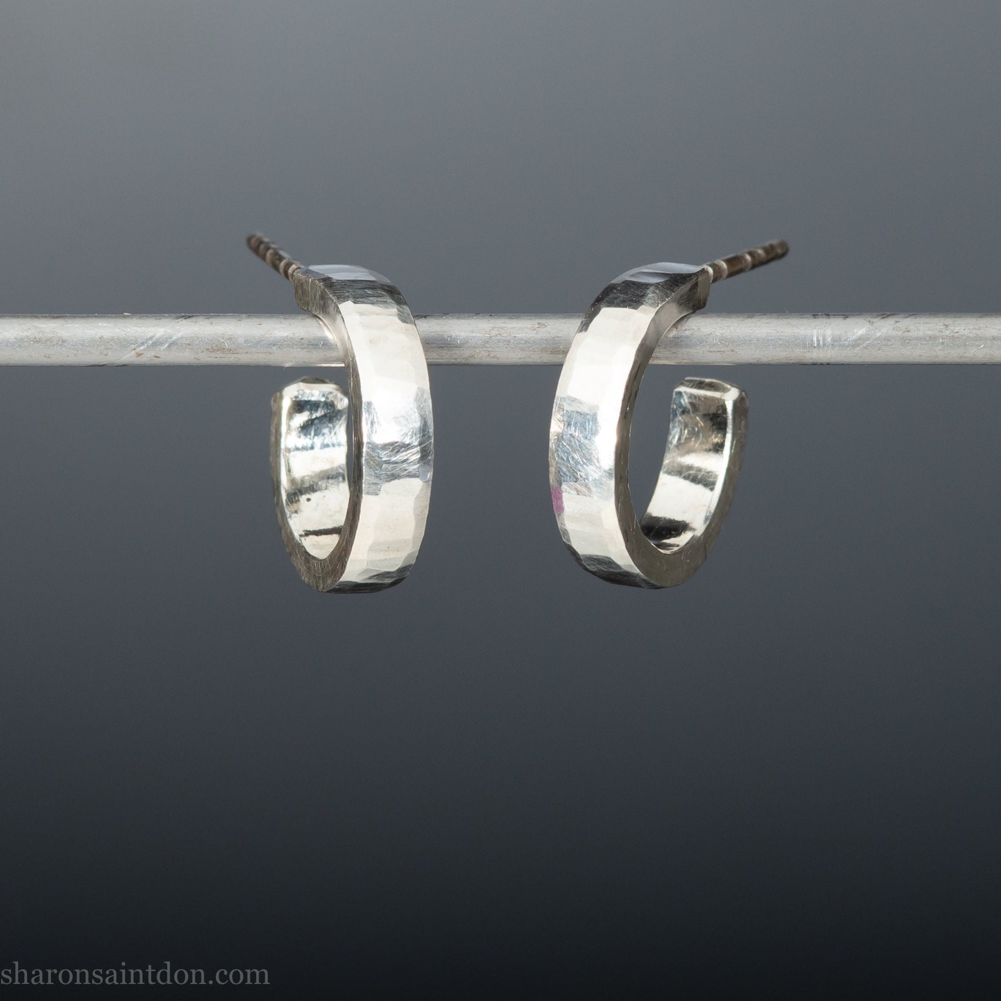 Close up photo of handcrafted 14mm x 3mm hammered solid sterling silver hoop earrings.
