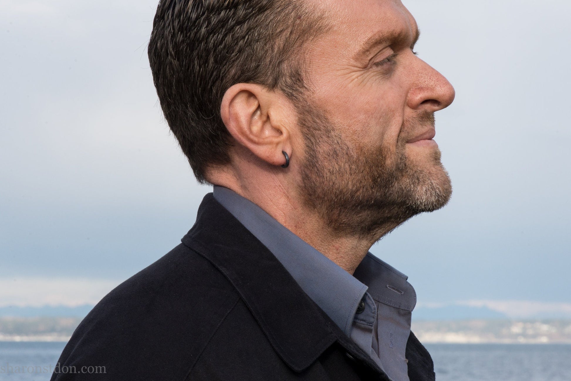 Small black hammered sterling silver hoop earrings worn by man, side profile, 14x2mm