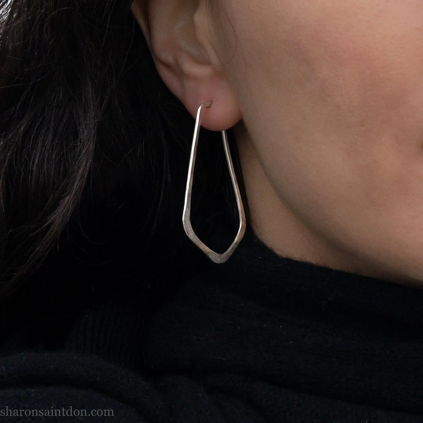 Sterling silver teardrop elongated shape hoop earrings, hammered matte finish, 50x32mm. Worn on an ear.