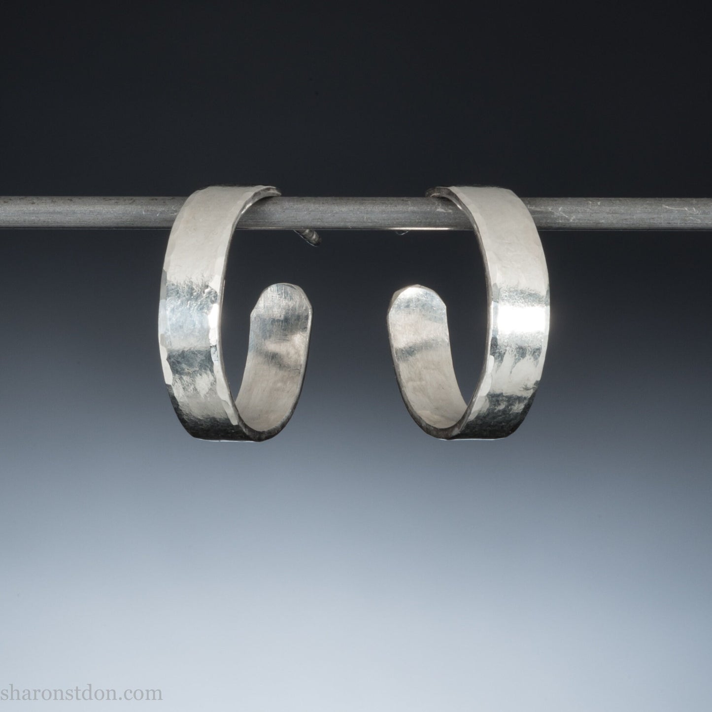 A close-up view of handcrafted solid silver hoop earrings, 18mm diameter with a hammered matte finish.