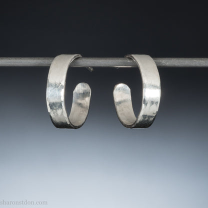 A close-up view of handcrafted solid silver hoop earrings, 18mm diameter with a hammered matte finish.