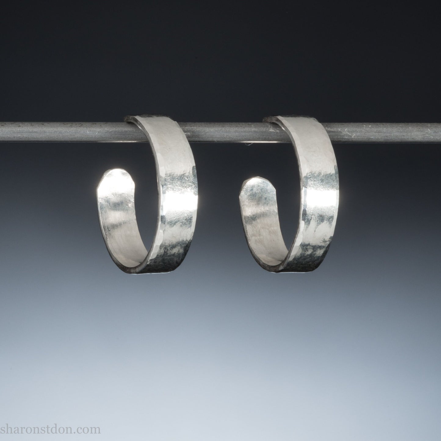 A close-up view of handcrafted solid silver hoop earrings, 18mm diameter with a hammered matte finish.