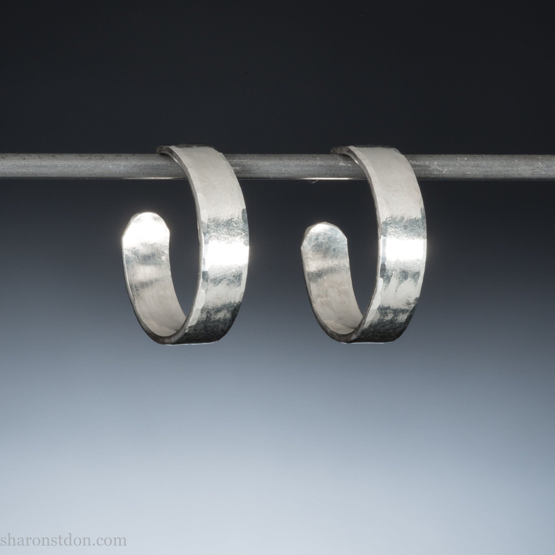 A close-up view of handcrafted solid silver hoop earrings, 18mm diameter with a hammered matte finish.