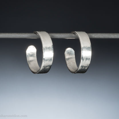 A close-up view of handcrafted solid silver hoop earrings, 18mm diameter with a hammered matte finish.