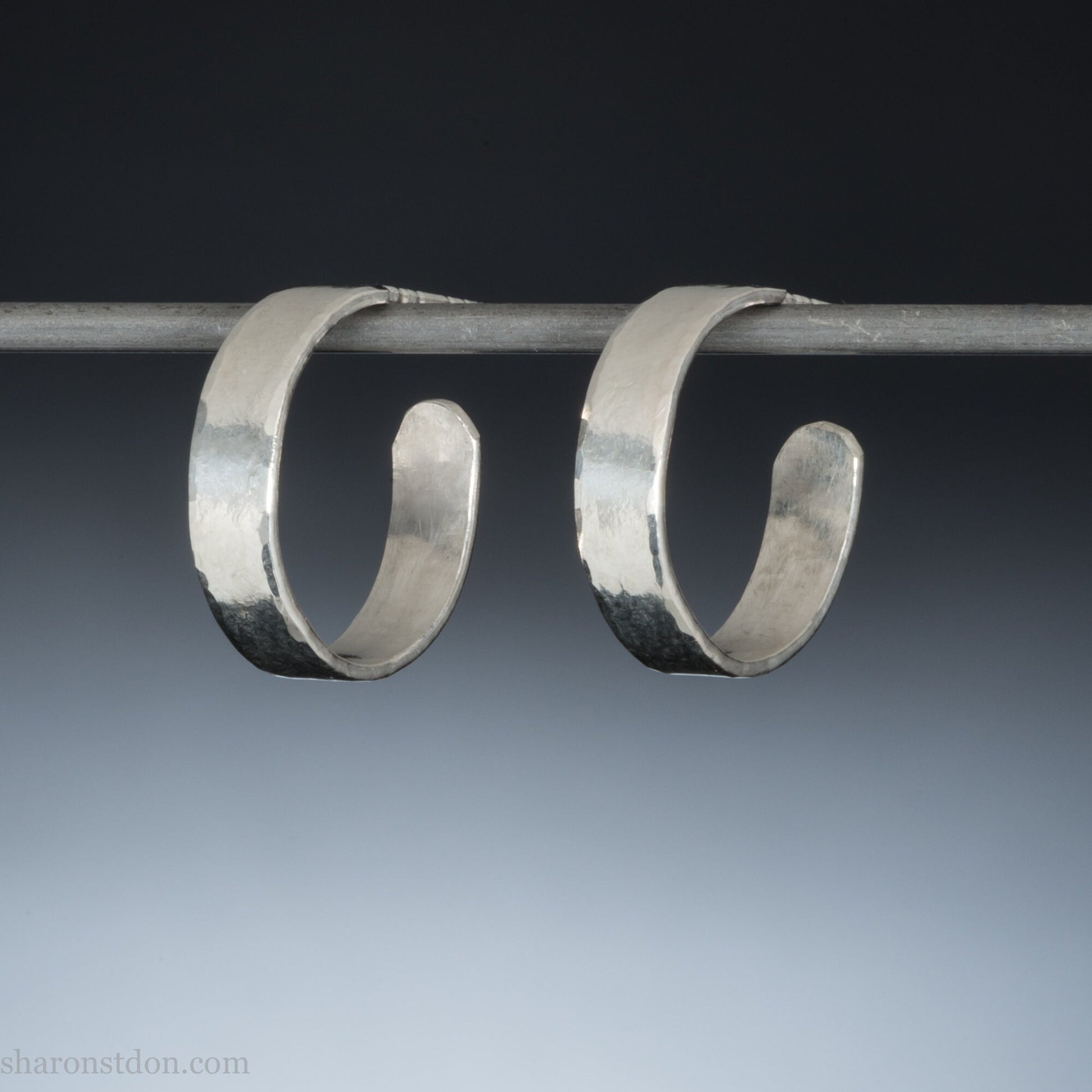 A close-up view of handcrafted solid silver hoop earrings, 18mm diameter with a hammered matte finish.
