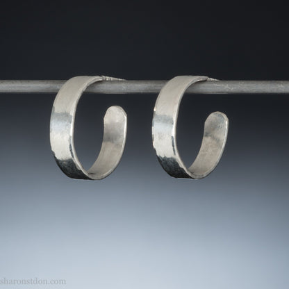 A close-up view of handcrafted solid silver hoop earrings, 18mm diameter with a hammered matte finish.